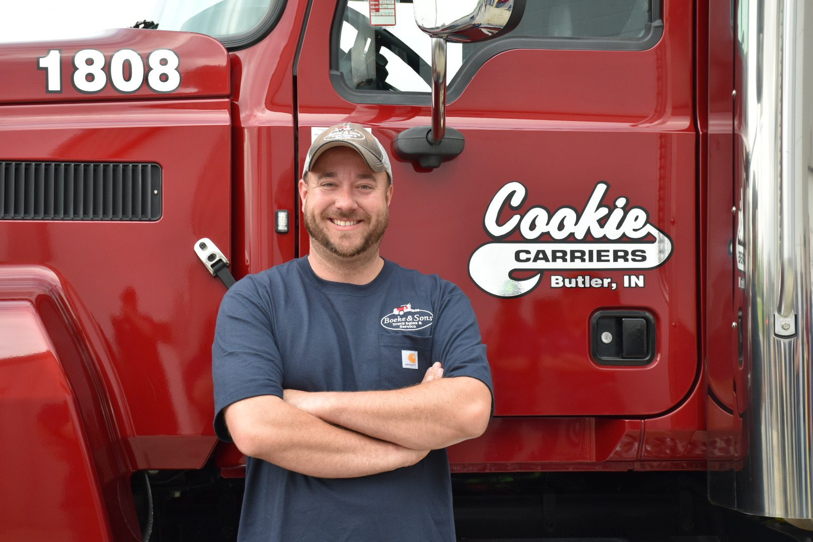 A man standing in front of a red truck.