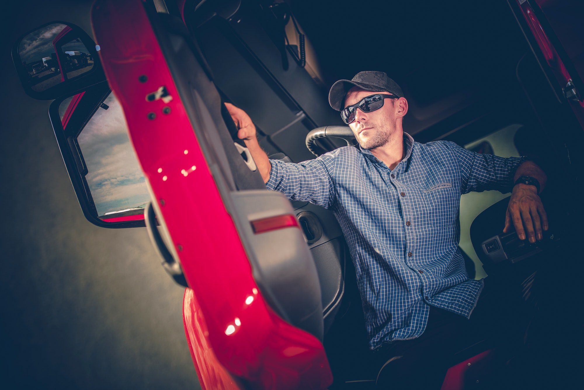 A man sitting on the seat of a bus holding onto a skateboard.